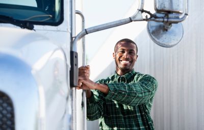 Smiling truck driver standing by his vehicle, ready for the road.