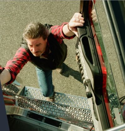 Man climbing into a vehicle, gripping the door and steps.