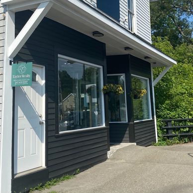 Exterior view of a black and white realty office with hanging flower baskets.