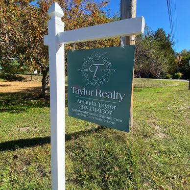 Real estate sign for Taylor Realty hanging on a white post outdoors.