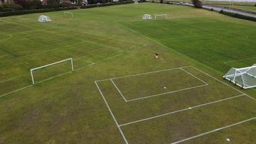 A large, empty soccer field with multiple goals and marked lines.