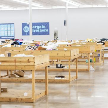 Empty wooden bins filled with scattered clothes in a discount store.