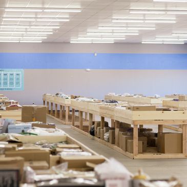 Empty wooden tables with boxes and packages in a warehouse-like space.