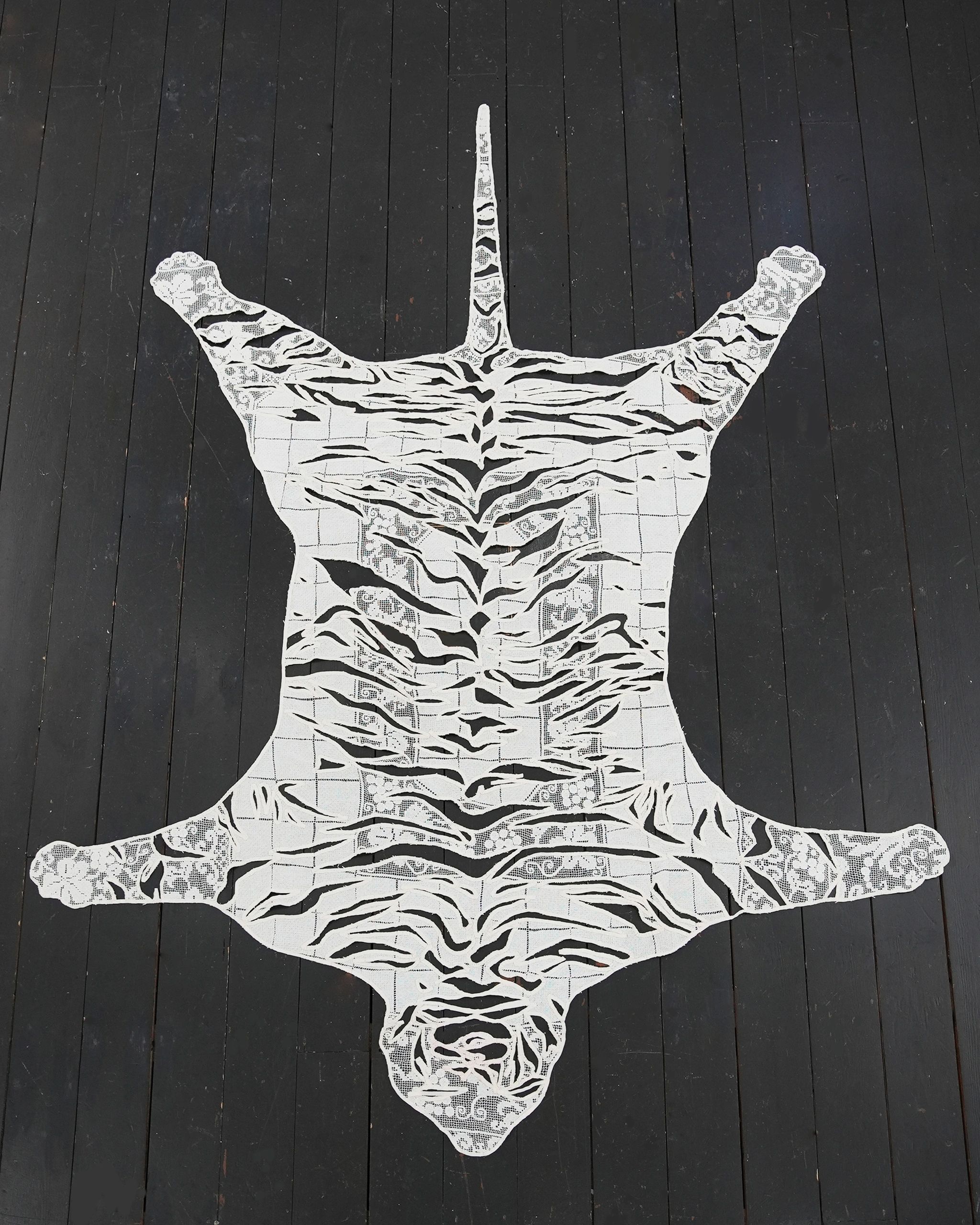 White lace tiger rug on dark wooden floor.