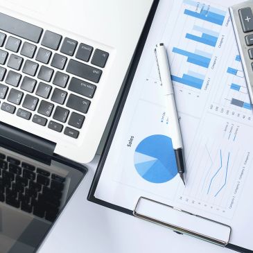 Laptop, grafikler ve hesap makinesi ile işyeri masası.