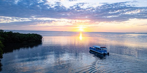 Boat sailing on calm water at sunset.