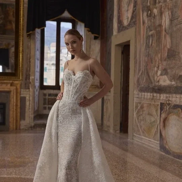 Woman in elegant white lace gown in ornate room.