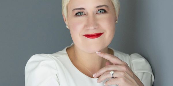 Woman with short blonde hair and red lipstick smiling.