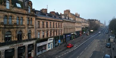 Historic buildings line a quiet street with few cars and pedestrians.