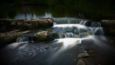A serene waterfall cascading over rocks in a forested area.