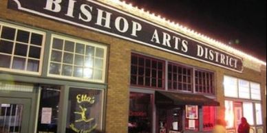 Night view of Bishop Arts District with lit storefronts and people walking.