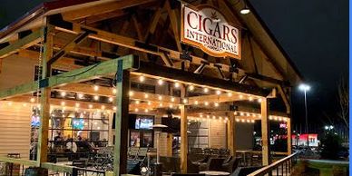 Outdoor cigar lounge with string lights at night.