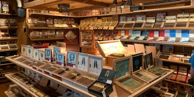A well-stocked cigar shop with various brands displayed on wooden shelves.