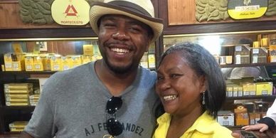Two people smiling and posing in a store with cigar displays.