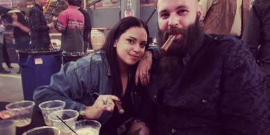 Couple enjoying cigars and drinks at a lively indoor event.