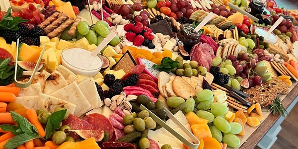 A colorful charcuterie board with assorted fruits, cheeses, meats, and crackers.