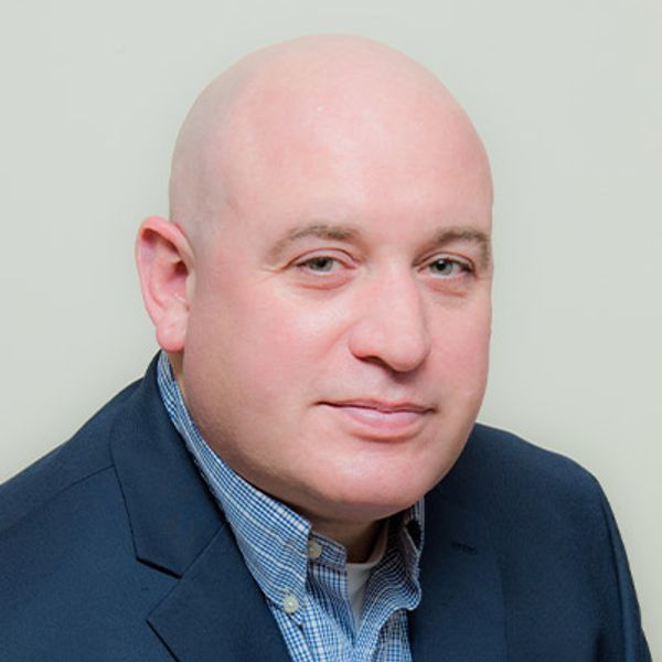 Portrait of a bald man in a blazer.