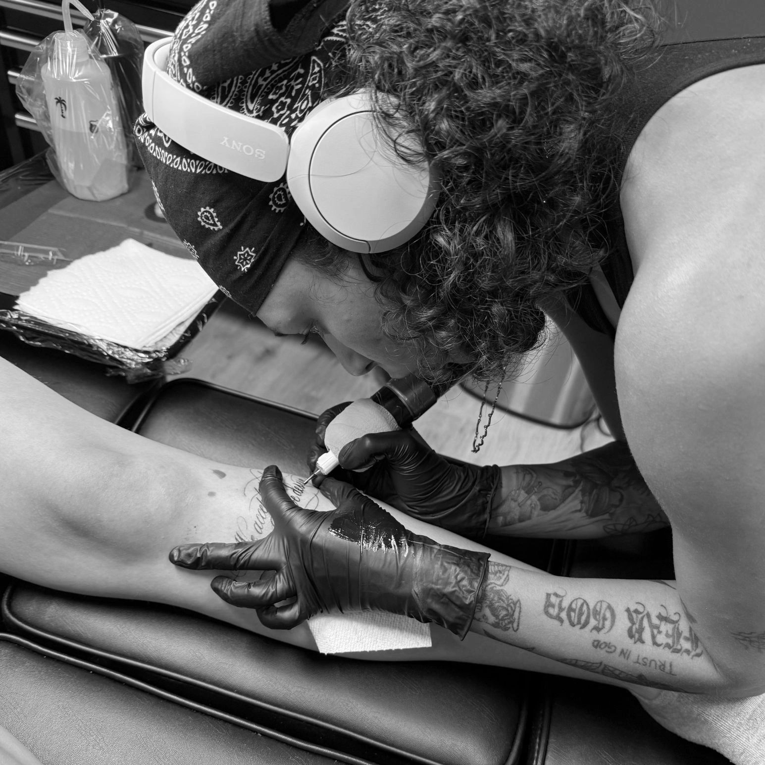 Tattoo artist carefully working on a client's leg tattoo.