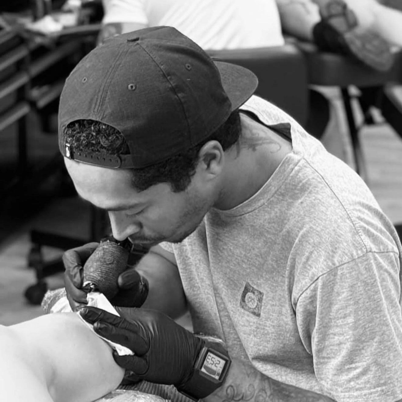 Tattoo artist focused on inking a client's leg.