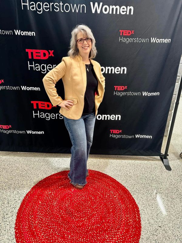 Woman posing on a red circle at TEDx Hagerstown Women event.