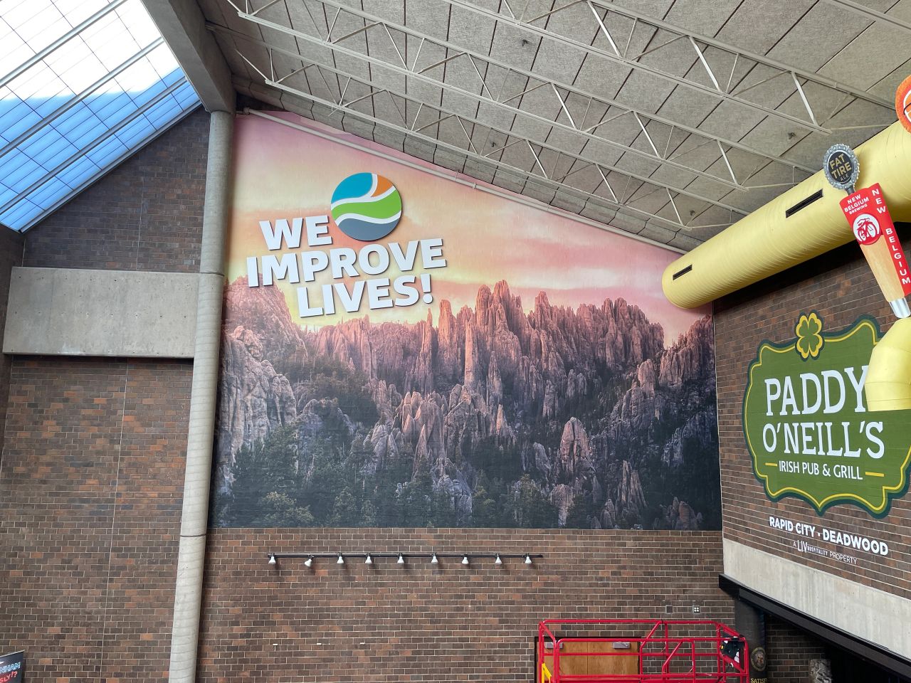 Large landscape wall mural featuring the words We Improve Lives