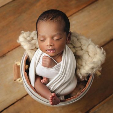 Ensaio newborn em estúdio de fotografia com cenário de madeiras no fundo