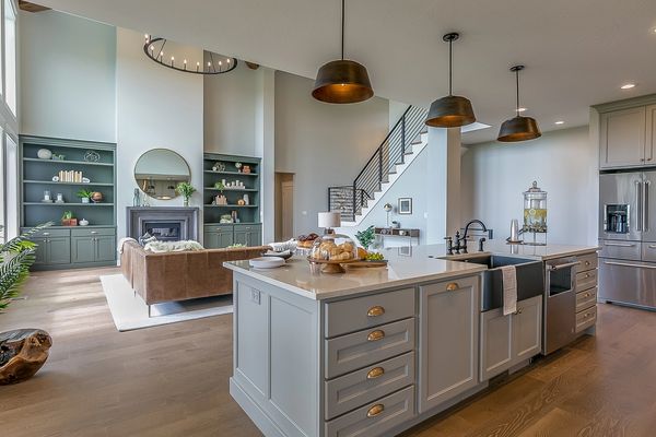 Spacious open-plan living area with a grey kitchen island, brown sofa, and high ceilings.