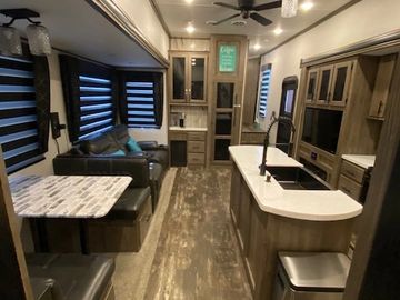 Modern RV interior with kitchen, dining, and lounge areas.