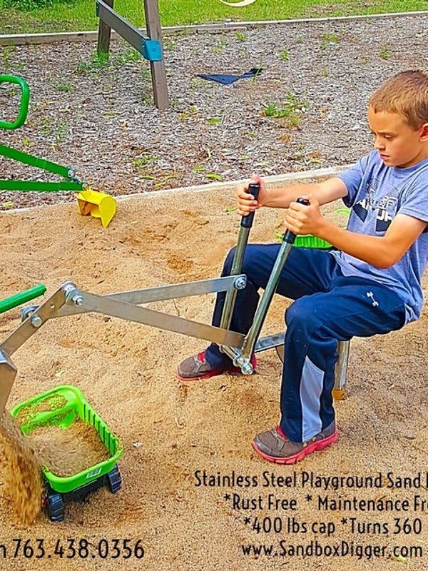 Boy playing on a stainless steel playground sand digger.