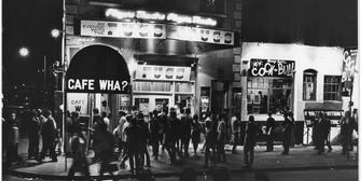 Crowd gathers outside Cafe Wha? at night.