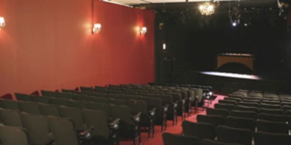 Empty auditorium with rows of chairs and a stage.
