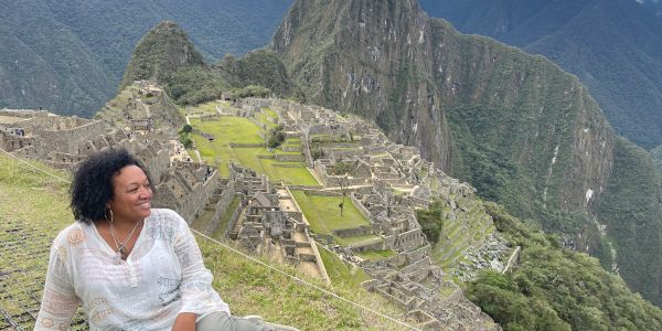 A woman smiling with Machu Picchu ruins in the background.