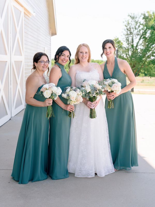 Bride with bridesmaids holding bouquets outdoors.