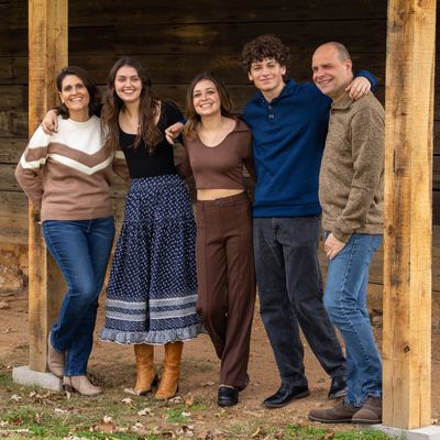 Gardner family of five poses together against a rustic wooden backdrop.
