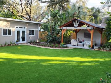 A backyard with lush green grass and a wooden gazebo.