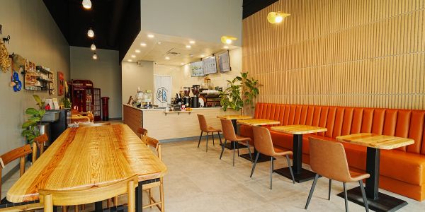Modern cozy cafe interior with wooden tables and orange seating.