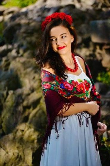 Woman in traditional floral dress and red accessories.