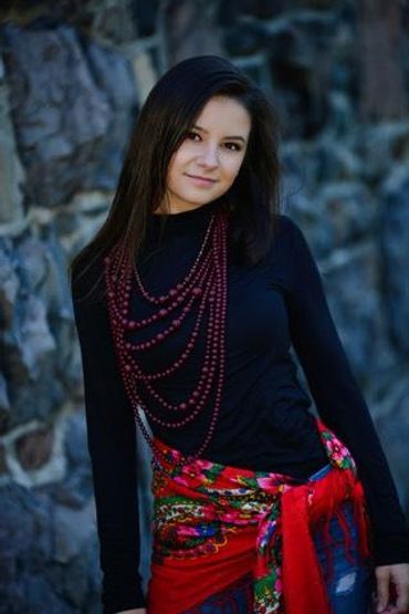 Young woman with long dark hair wearing colorful accessories.