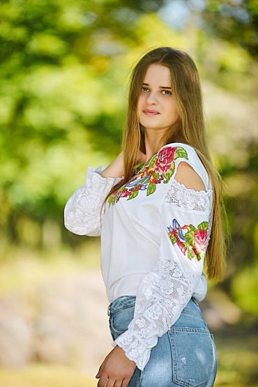 Young woman in embroidered blouse outdoors.