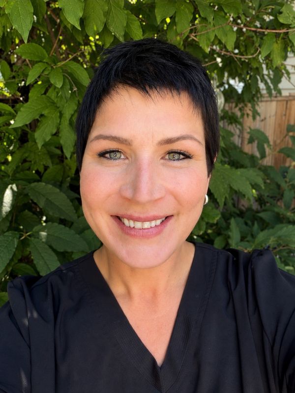 Smiling woman with short black hair outdoors.