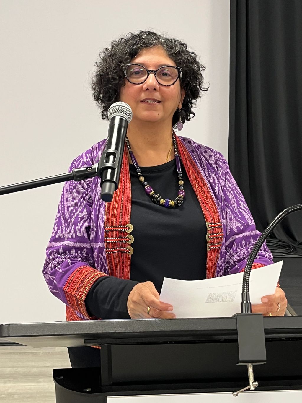 Woman speaking at a podium with papers.