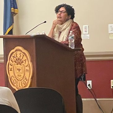 Speaker at a podium with Keene State College logo.