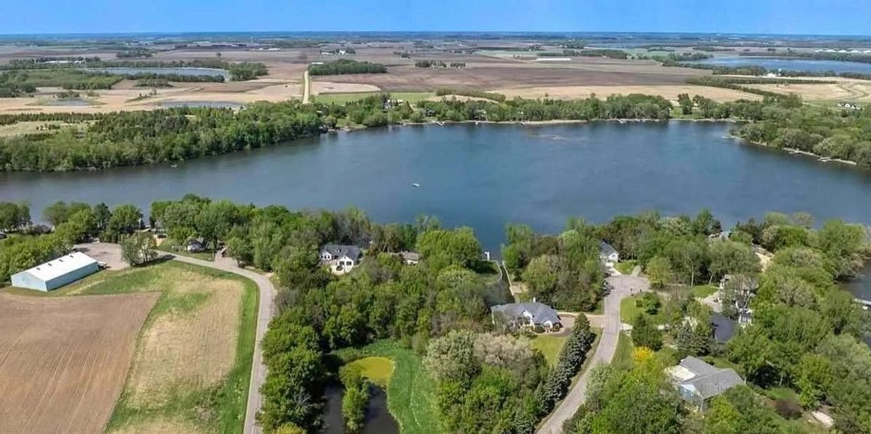 A lake surrounded by houses, trees, and farmland.