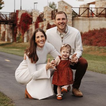 Happy family of three posing outdoors on a path with autumn colors.