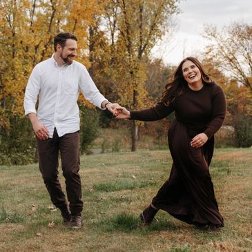 Couple joyfully holding hands and walking in autumn park.