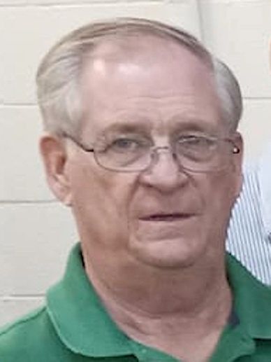 An older man wearing glasses and a green polo shirt.