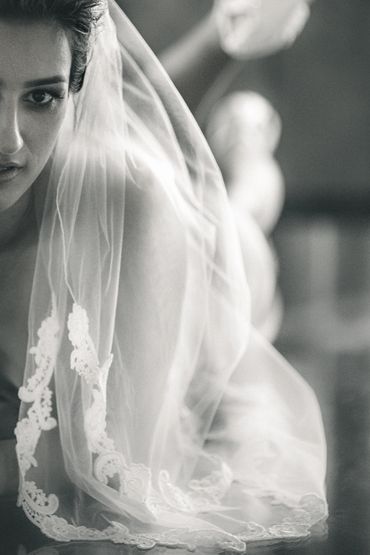 Close-up of a bride in a lace veil with a thoughtful expression.