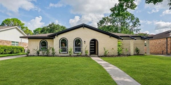 Single-story brick house with arched windows and a large lawn.