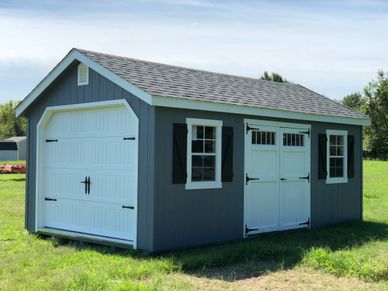 A gray shed with white garage door and double entry doors with windows.