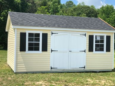 A yellow garden shed with white double doors and two windows with black shutters.